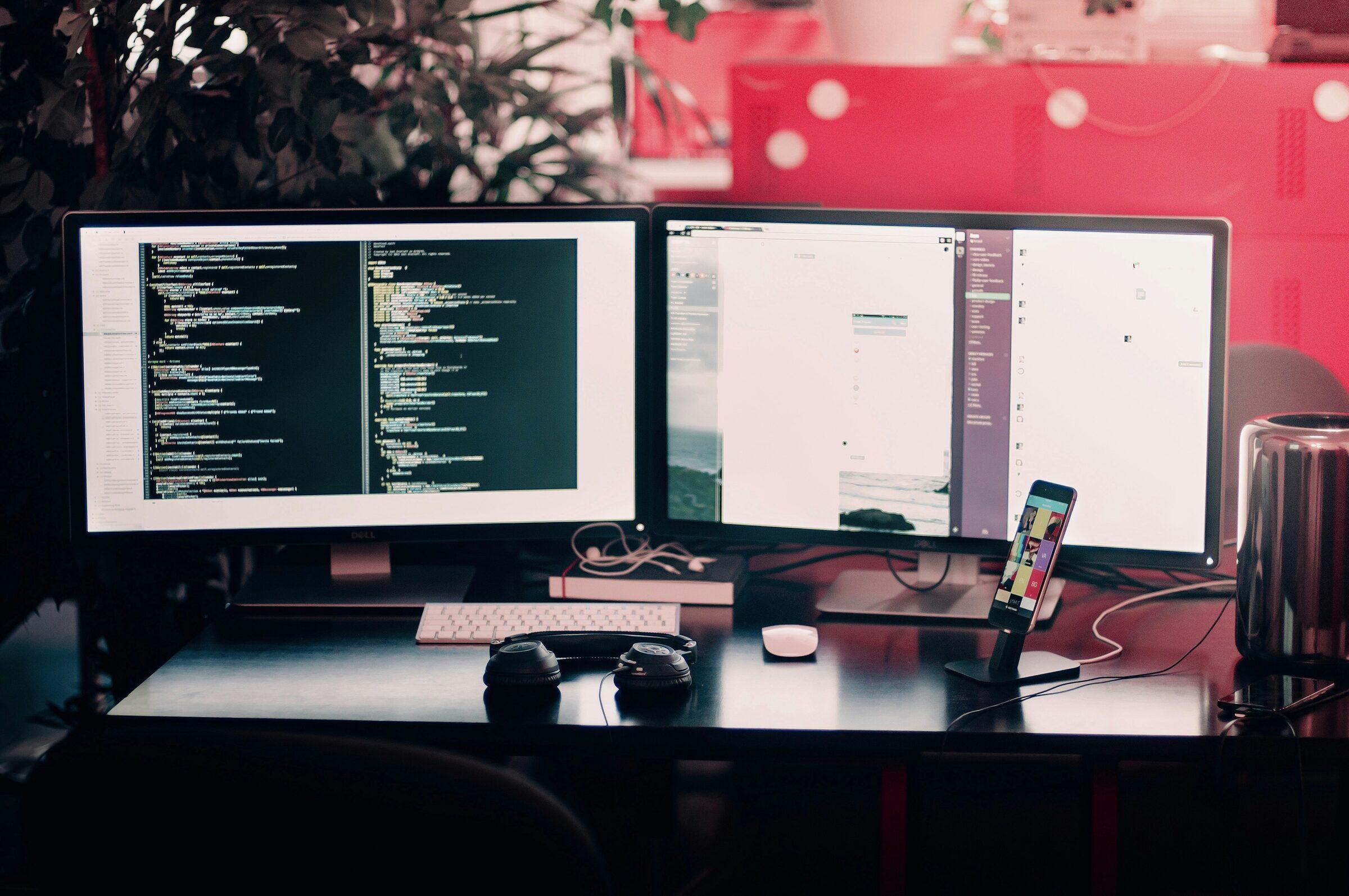 Developer workstation with two monitors displaying website code